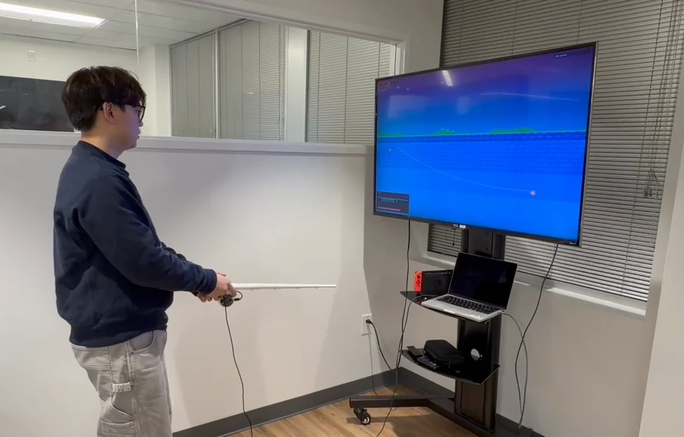 Playing Studio Waters: casting with the rod in hand, the game running on the screen behind