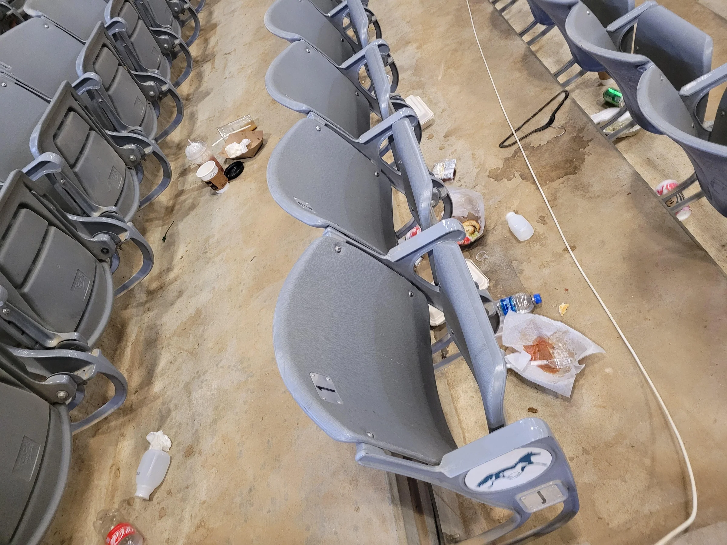 Stadium seats after an event: cups, food containers, and wrappers left between the rows